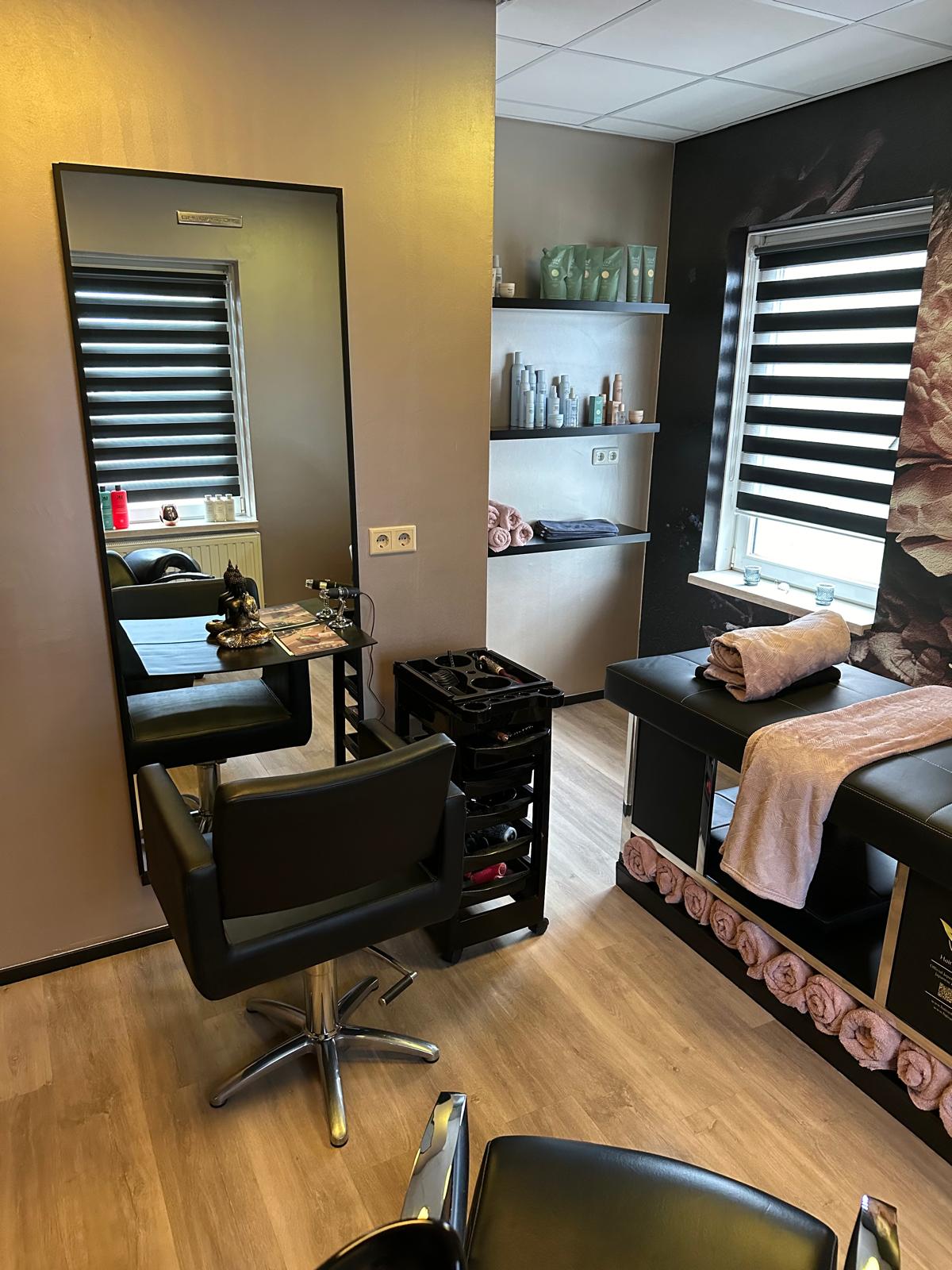 De salon met kapperstoel, spiegel en behandelbed