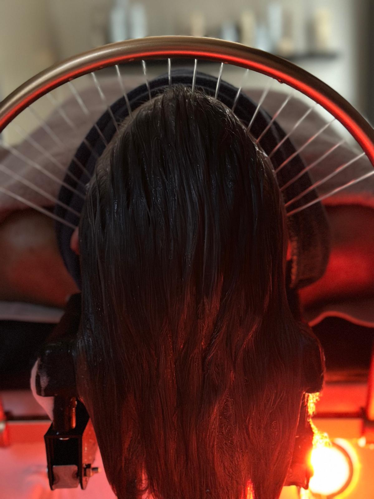 Haarbehandeling onder de verwarmde kap in de salon